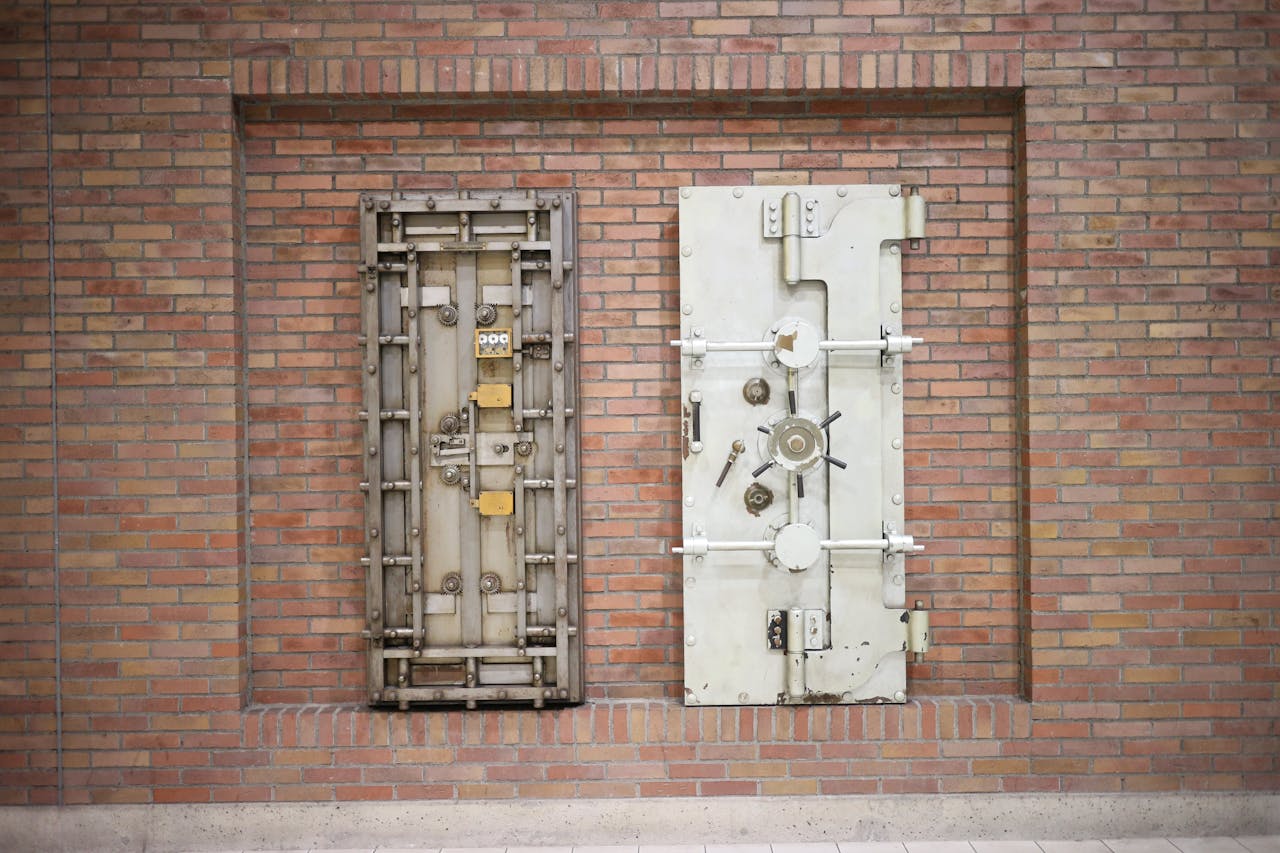 about-01 Two steel security vault doors attached to a vintage brick wall, showcasing industrial strength.