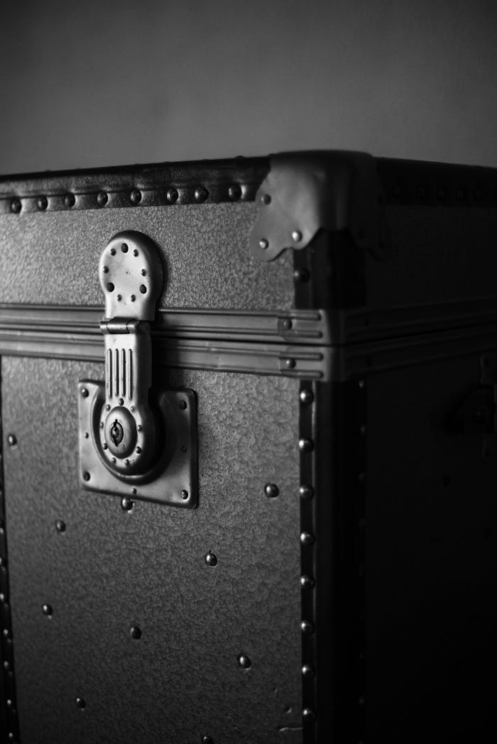 about-04 Close-up of a vintage metal chest with a detailed lock, captured in a classic black and white style.